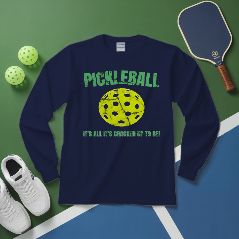 Navy blue long-sleeve shirt with pickleball graphic and text on a green and blue surface with pickleball equipment.