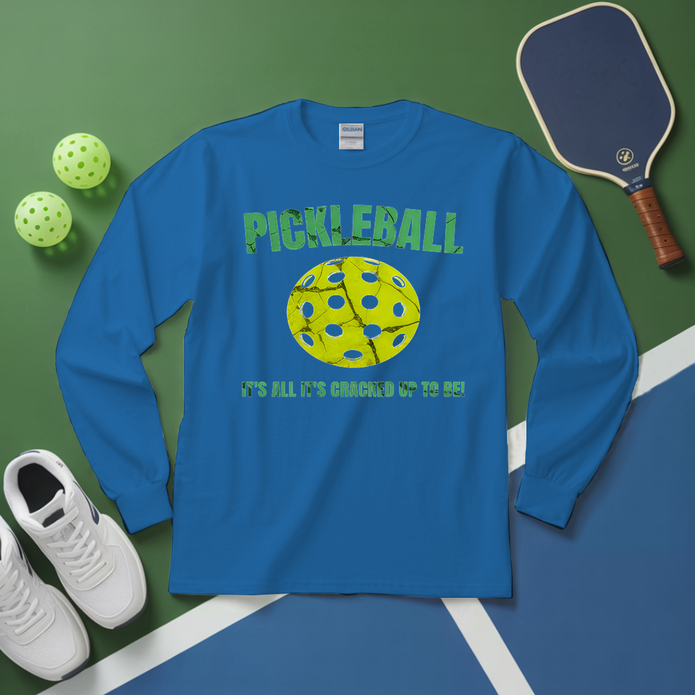 Blue long-sleeve shirt with pickleball design on a green and blue surface with pickleballs and paddle.