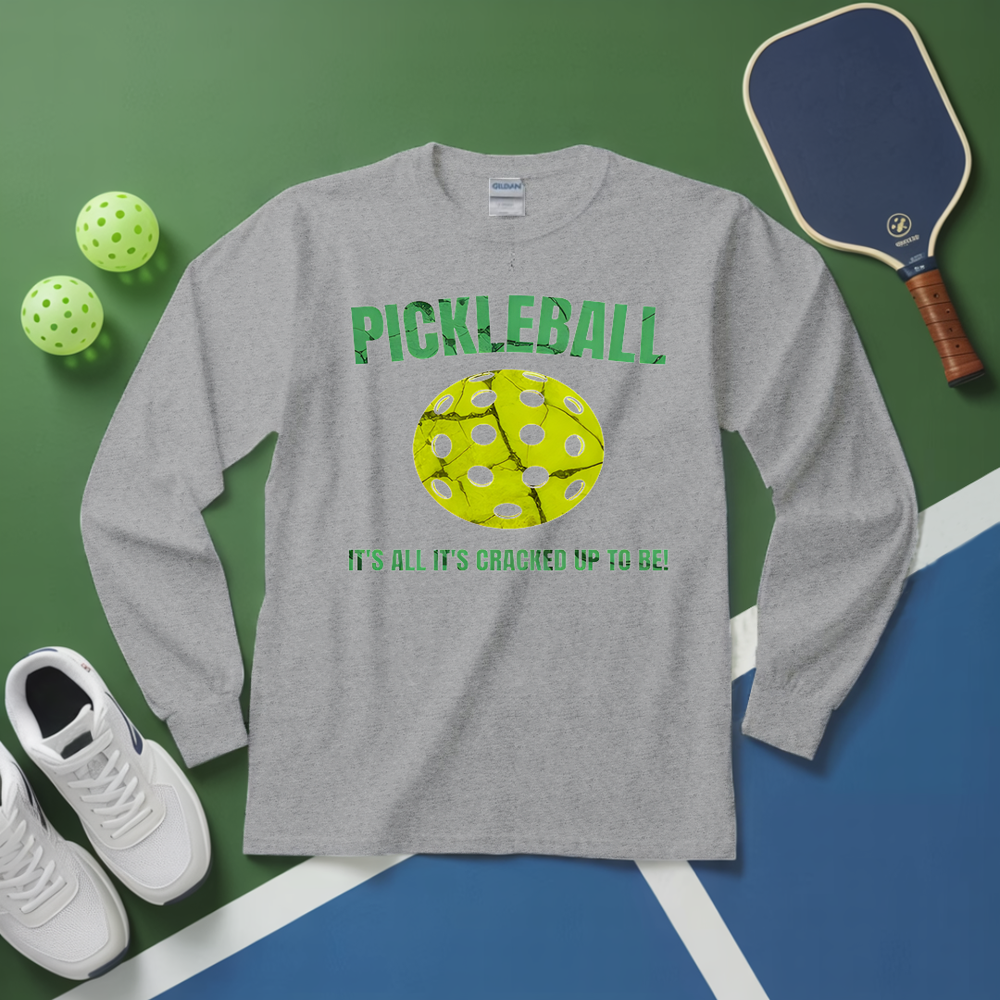 Gray long-sleeve shirt with pickleball graphic and text on a green and blue surface with pickleballs and paddle.