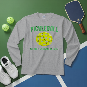 Gray long-sleeve shirt with pickleball graphic and text on a green and blue surface with pickleballs and paddle.