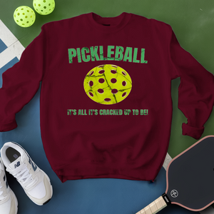 Maroon sweatshirt with pickleball graphic and text on a green and blue background