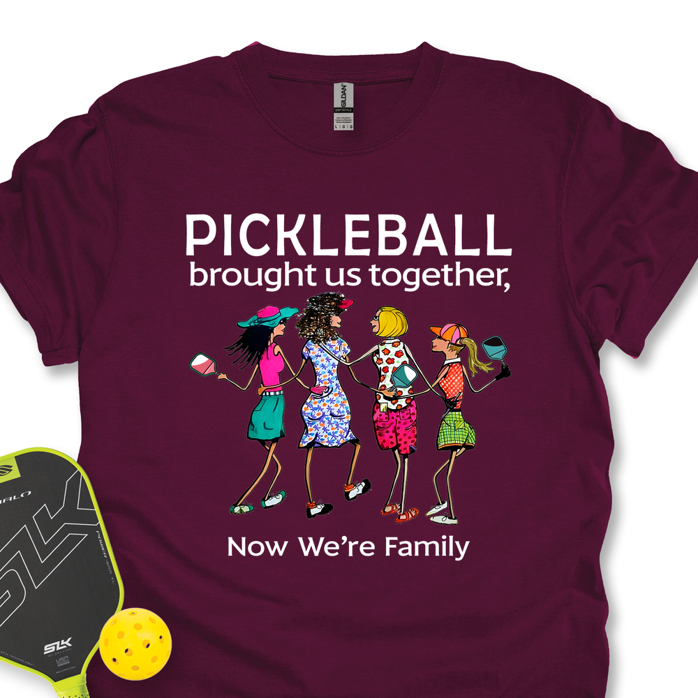 Maroon t-shirt with pickleball-themed design and accessories on a white background