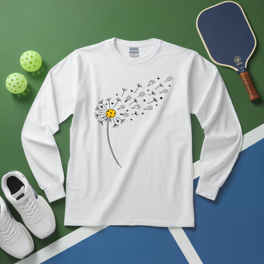 White long-sleeve shirt with dandelion graphic, pickleball balls, paddle, and shoes on a green and blue background