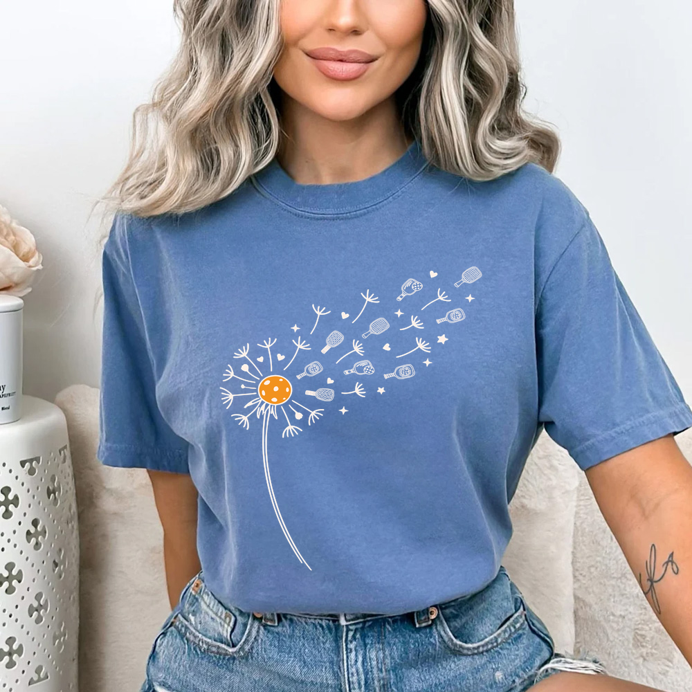 Woman wearing a blue t-shirt with a dandelion graphic design.