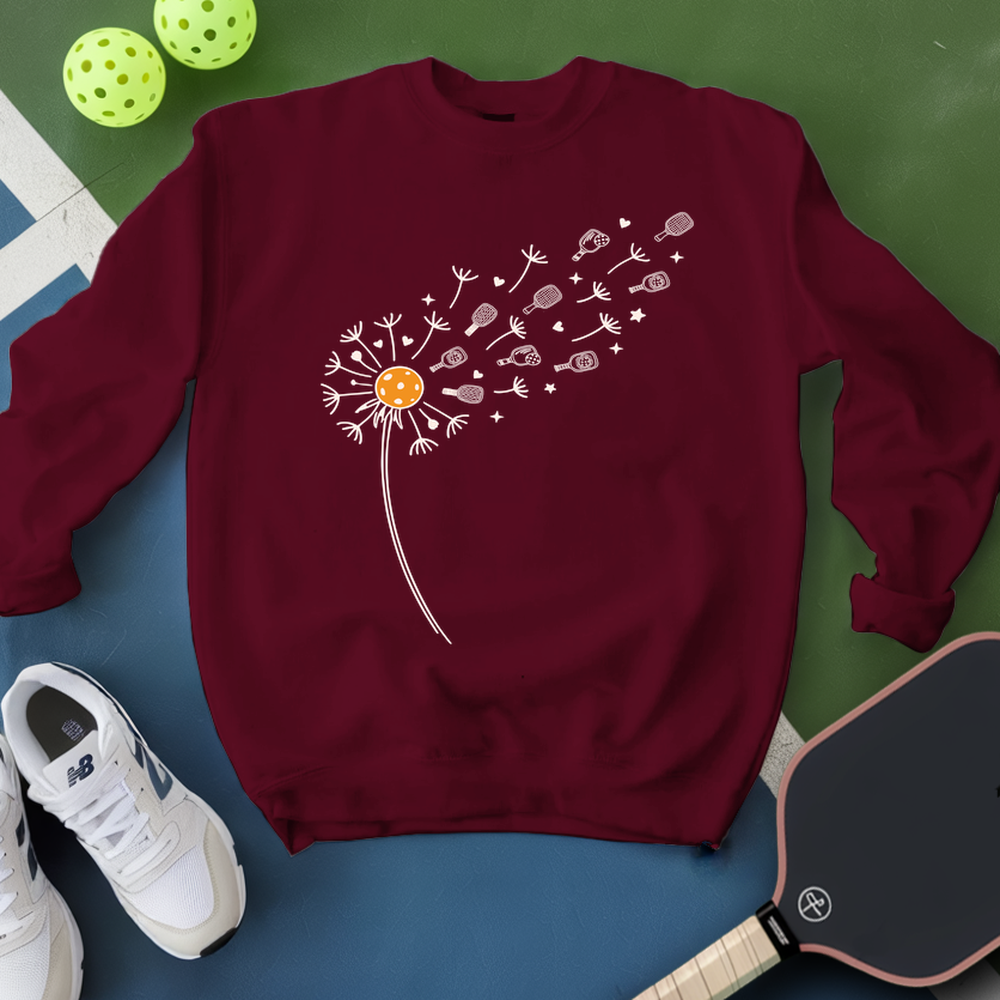 Maroon sweatshirt with dandelion graphic on a blue and green background