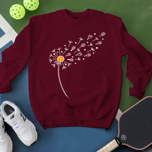 Maroon sweatshirt with dandelion graphic on a blue and green background