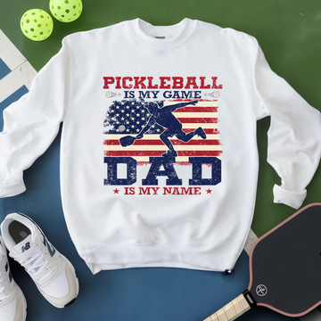 White sweatshirt with pickleball-themed design on a green and blue background