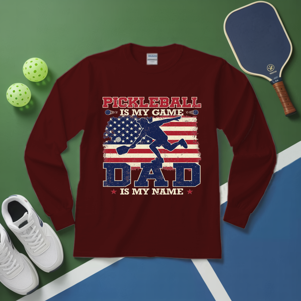 Maroon long-sleeve shirt with pickleball design on a green and blue surface with pickleball equipment.
