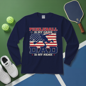 Navy blue sweatshirt with pickleball design on a green and blue surface with pickleball equipment.