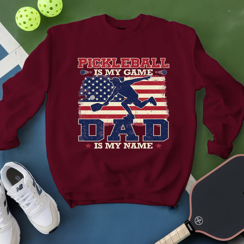Maroon sweatshirt with pickleball design and text on a blue and green background