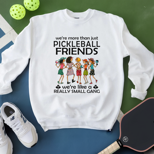 White sweatshirt with pickleball-themed design on a green and blue surface with pickleballs and a paddle.