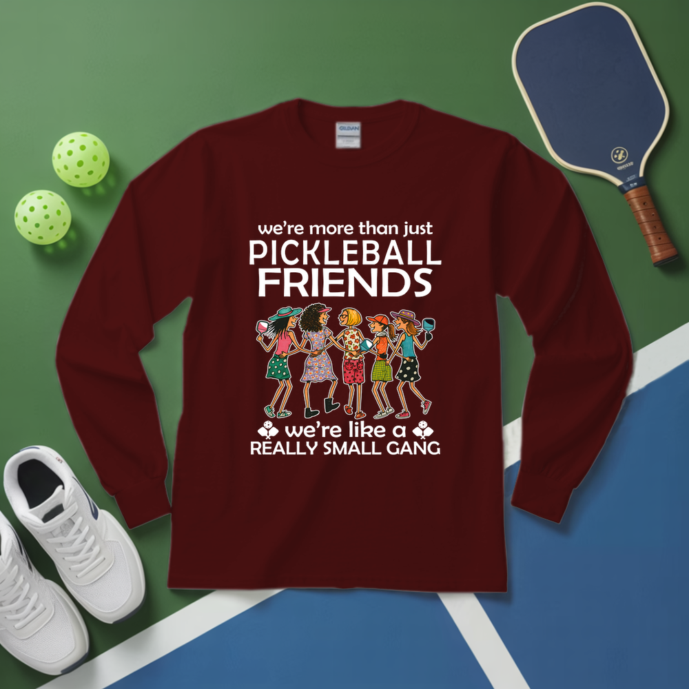 Maroon long-sleeve shirt with pickleball-themed design on a green and blue surface with pickleballs and a paddle.