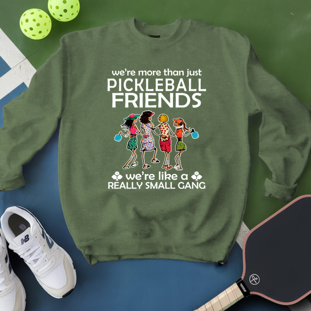 Green sweatshirt with pickleball-themed design on a blue surface with pickleballs and a paddle.
