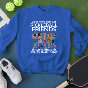 Blue sweatshirt with pickleball-themed design on a green surface with pickleballs and a paddle.