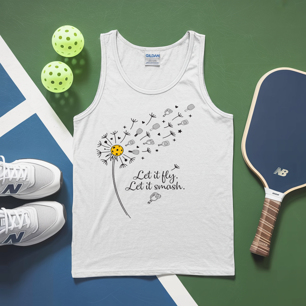 White tank top with dandelion design and text, placed on a green and blue surface with pickleballs and a paddle.