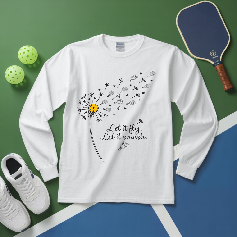 White long-sleeve shirt with dandelion graphic and text, placed on a green and blue surface with sports equipment.