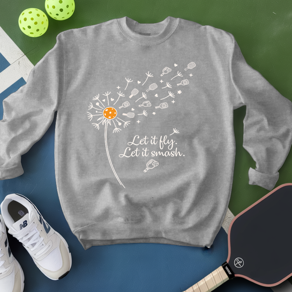 Gray sweatshirt with dandelion design and text, placed on a green and blue surface with sports equipment.
