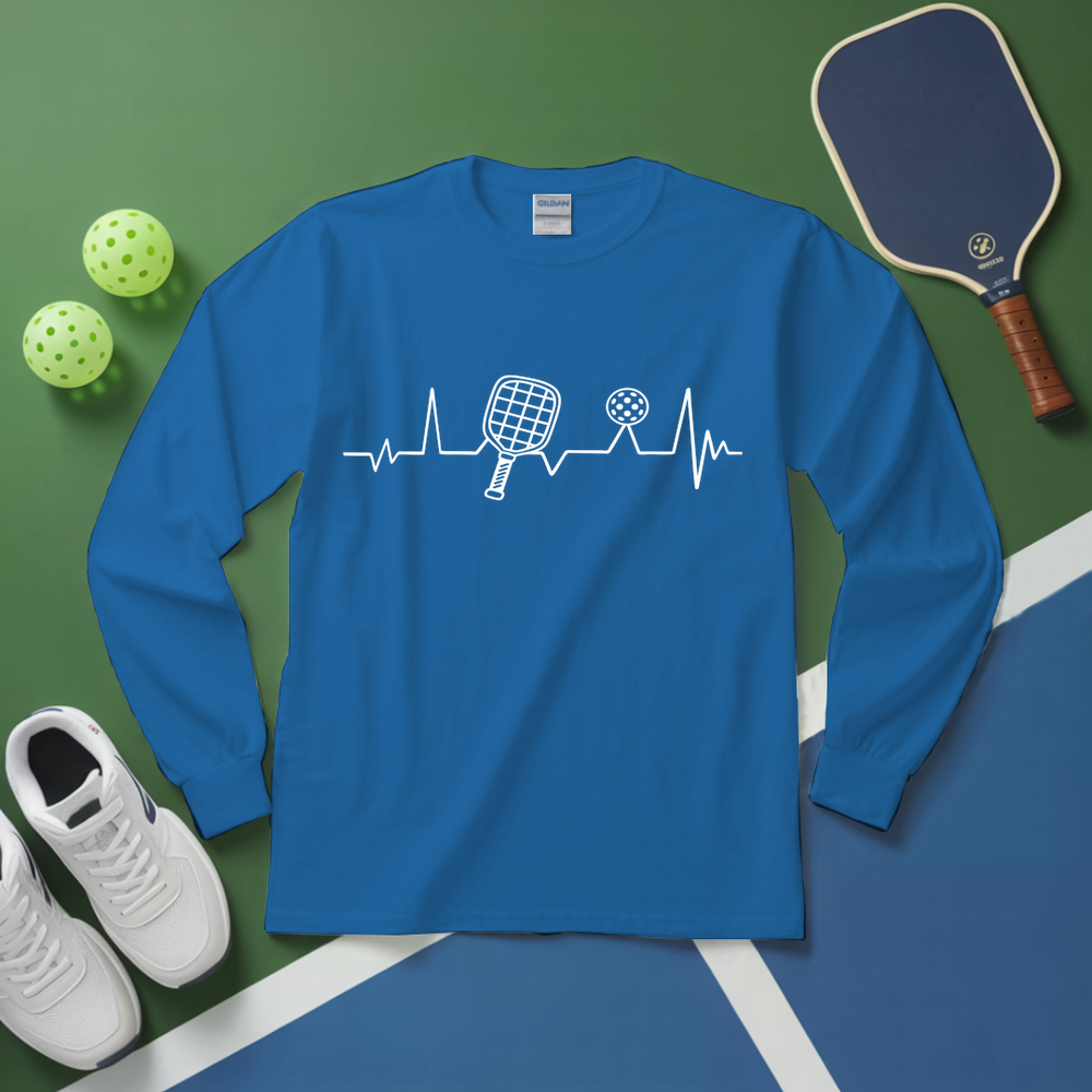 Blue long-sleeve shirt with pickleball design on a green and blue surface with pickleball equipment.