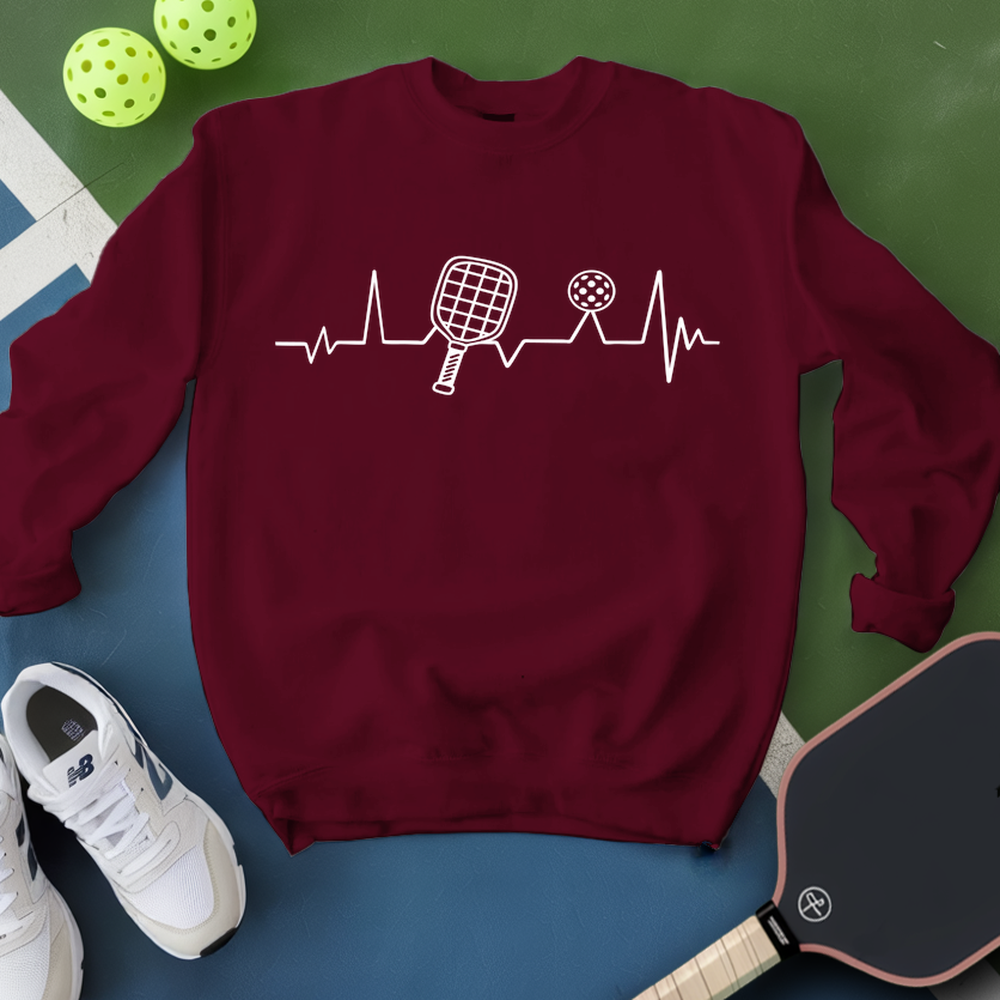 Maroon sweatshirt with pickleball design on a green and blue background