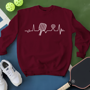 Maroon sweatshirt with pickleball design on a green and blue background