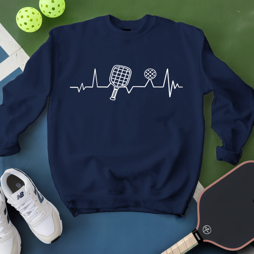 Navy blue sweatshirt with pickleball design on a green and blue surface with pickleballs and a paddle.