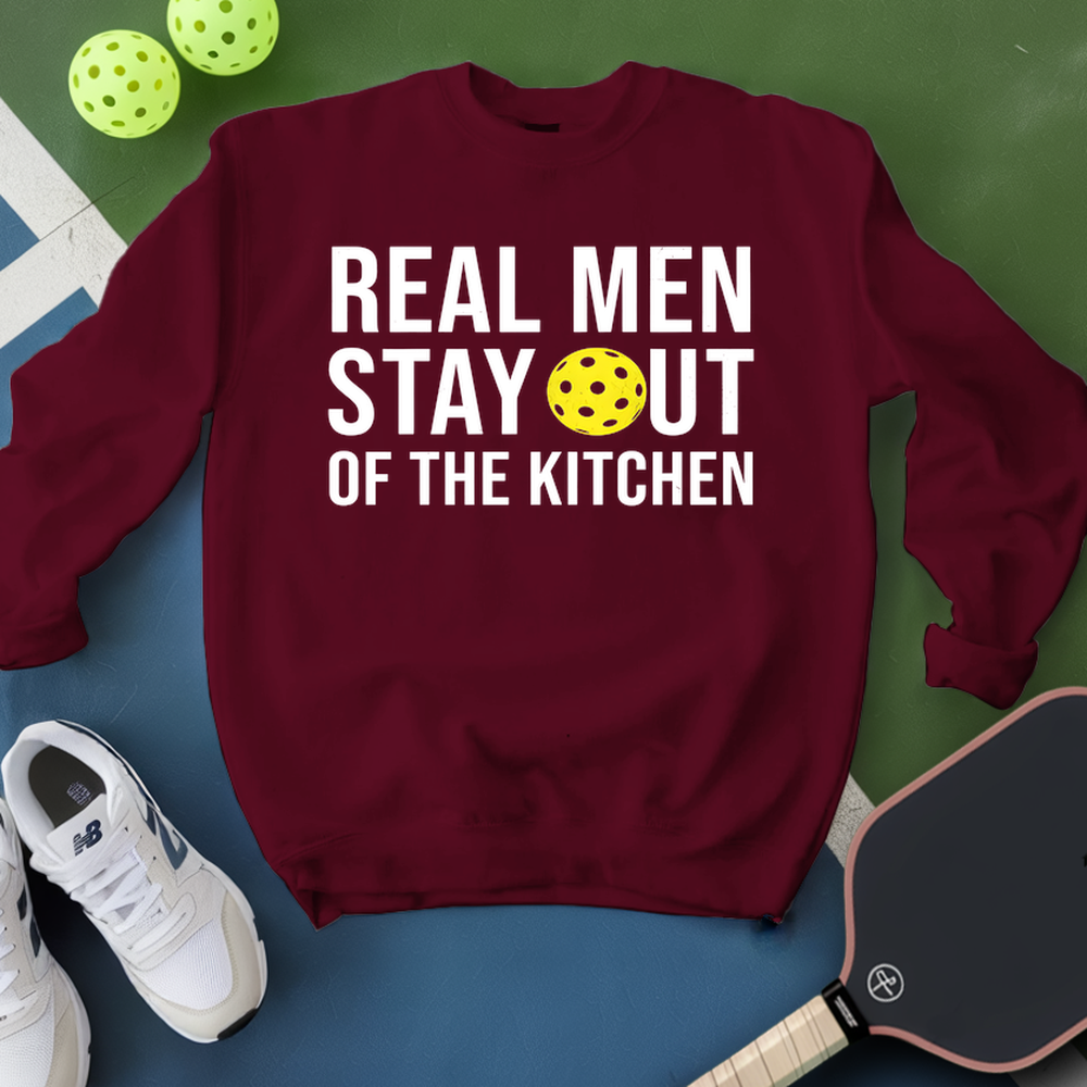 Maroon sweatshirt with 'Real Men Stay Out of the Kitchen' text and pickleball elements on a green and blue background.