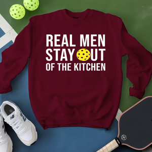 Maroon sweatshirt with 'Real Men Stay Out of the Kitchen' text and pickleball elements on a green and blue background.