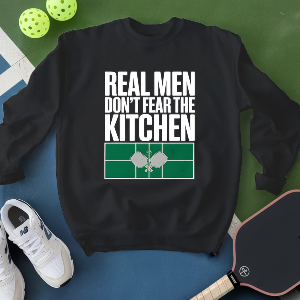 Black sweatshirt with 'Real Men Don't Fear The Kitchen' text and pickleball elements on a green and blue background.