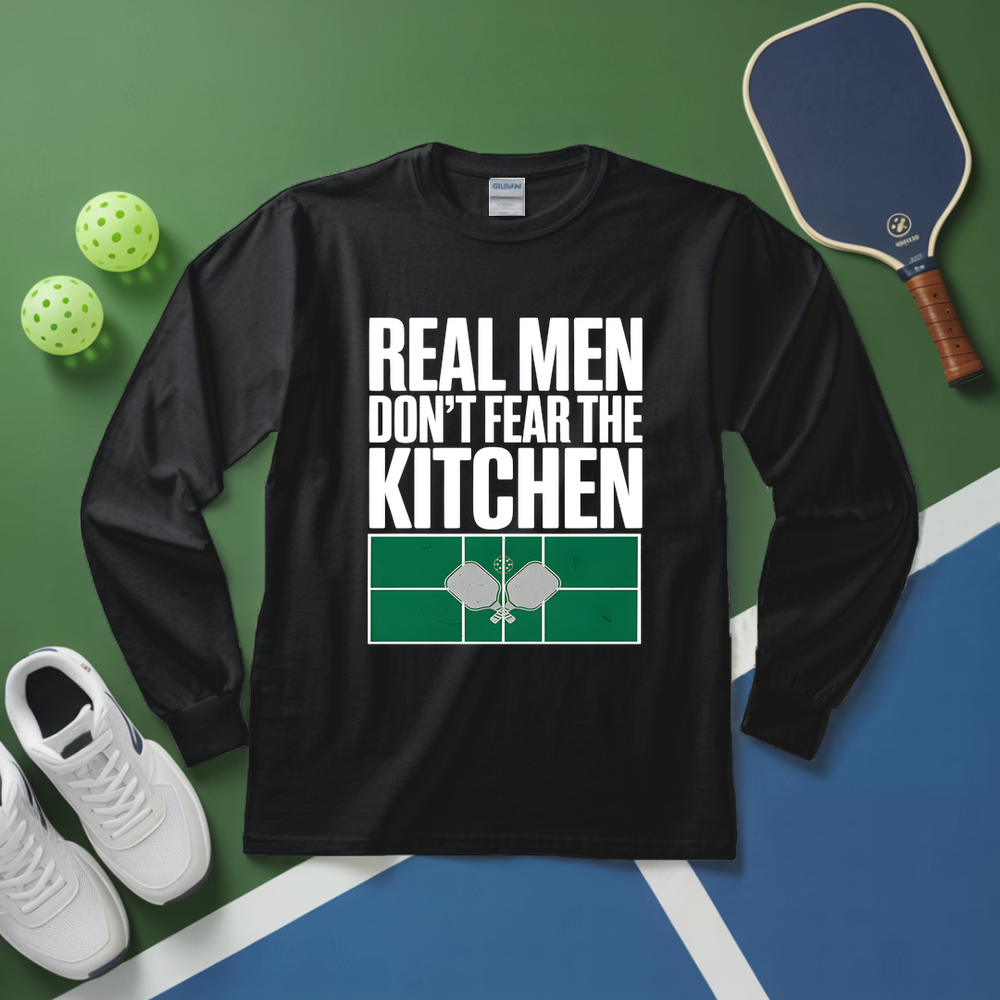Black long-sleeve shirt with 'Real men don't fear the kitchen' text on a green and blue background with pickleball equipment.