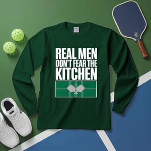 Green long-sleeve shirt with 'Real men don't fear the kitchen' text on a green and blue background with sports equipment.