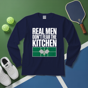 Navy blue sweatshirt with 'Real men don't fear the kitchen' text on a green and blue background with pickleball equipment.