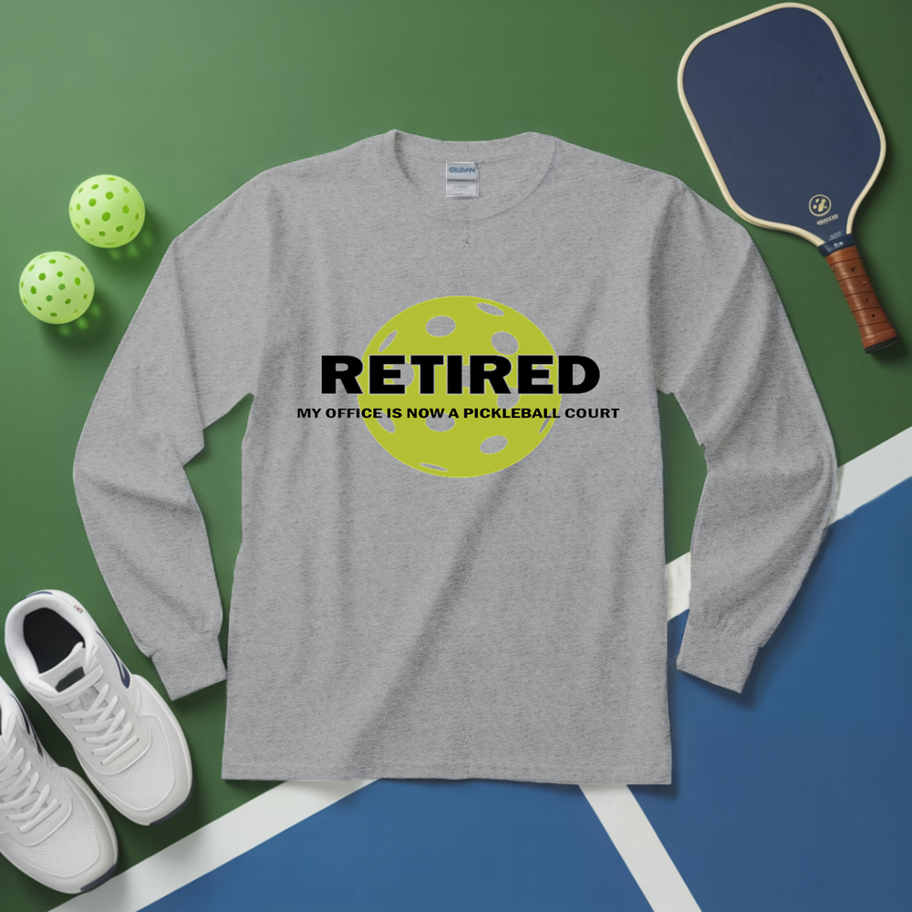 Gray long-sleeve shirt with pickleball-themed design on a green and blue surface with pickleball equipment.