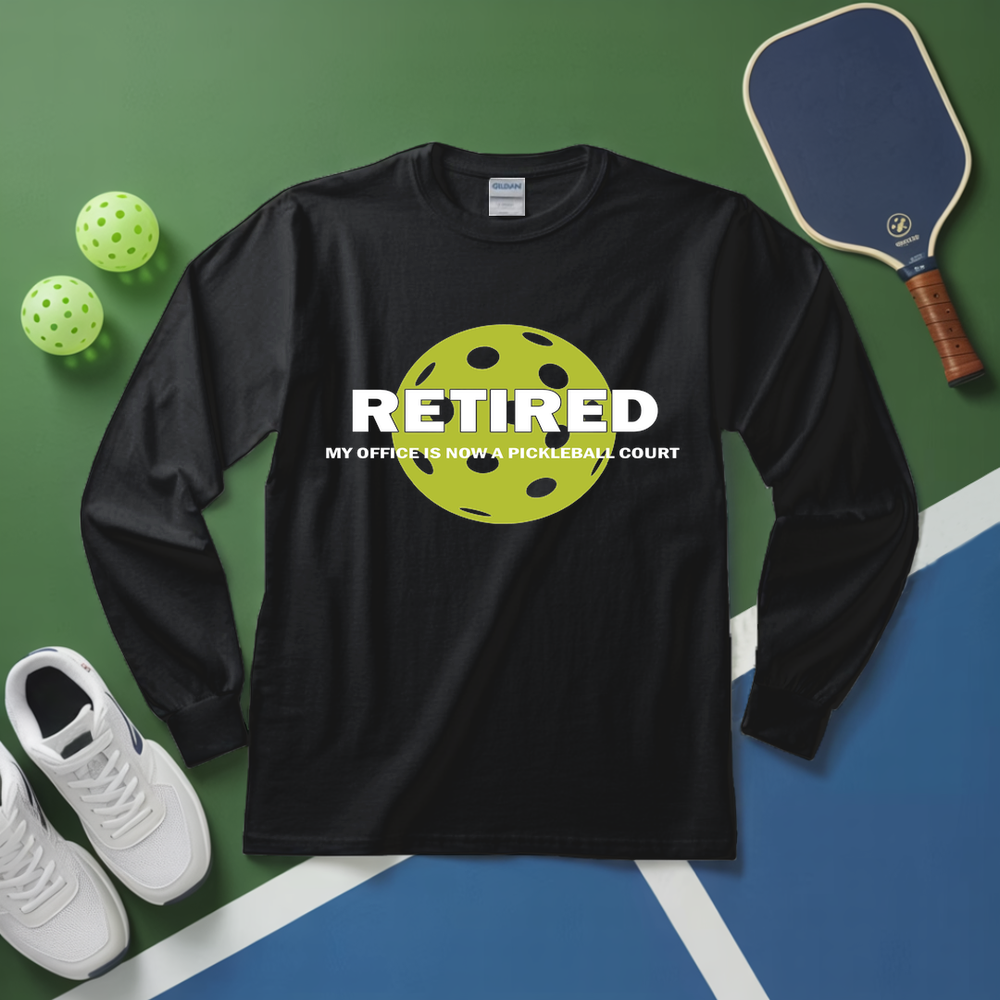 Black long-sleeve shirt with pickleball design and text on a green and blue surface with pickleball equipment.