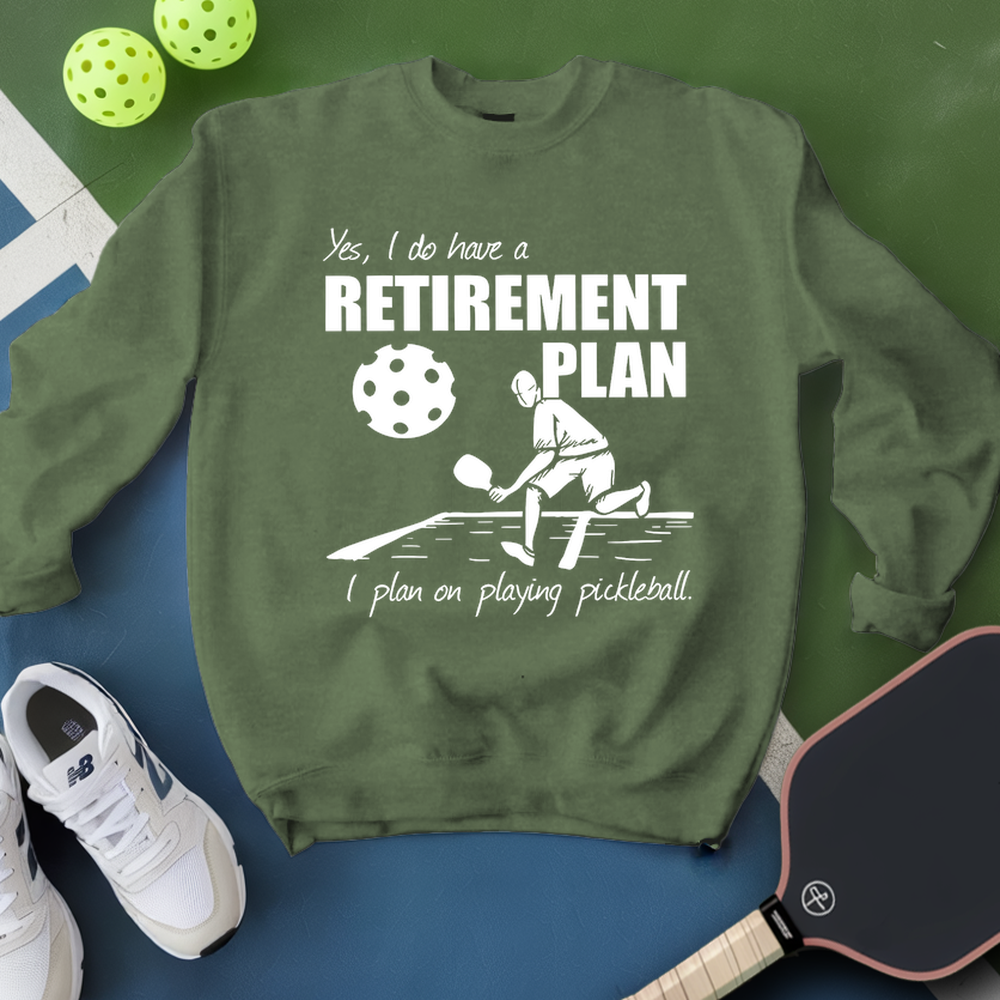 Green sweatshirt with pickleball-themed design and text, surrounded by pickleballs and a paddle on a green and blue background.