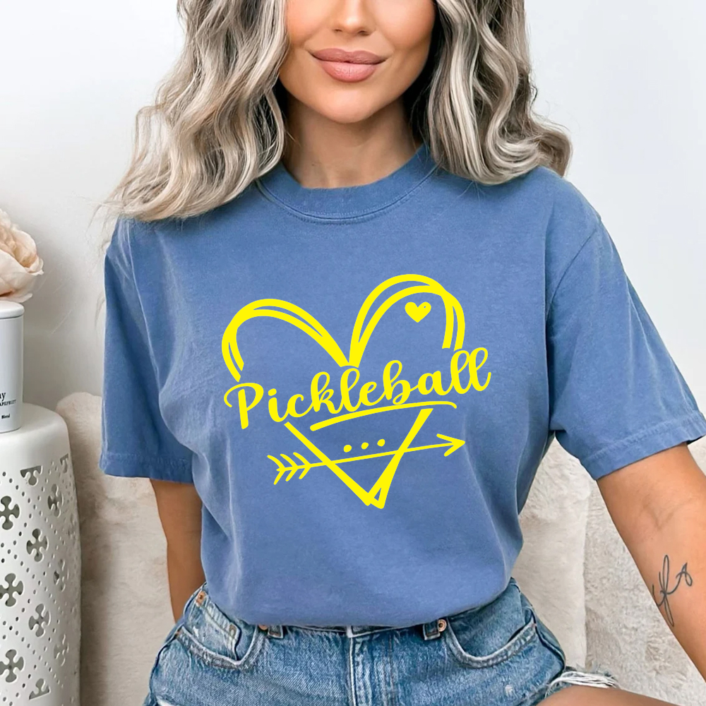 Woman wearing a blue t-shirt with a yellow pickleball design