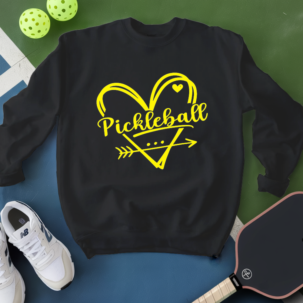 Black sweatshirt with yellow 'Pickleball' design on a blue surface with pickleball equipment.