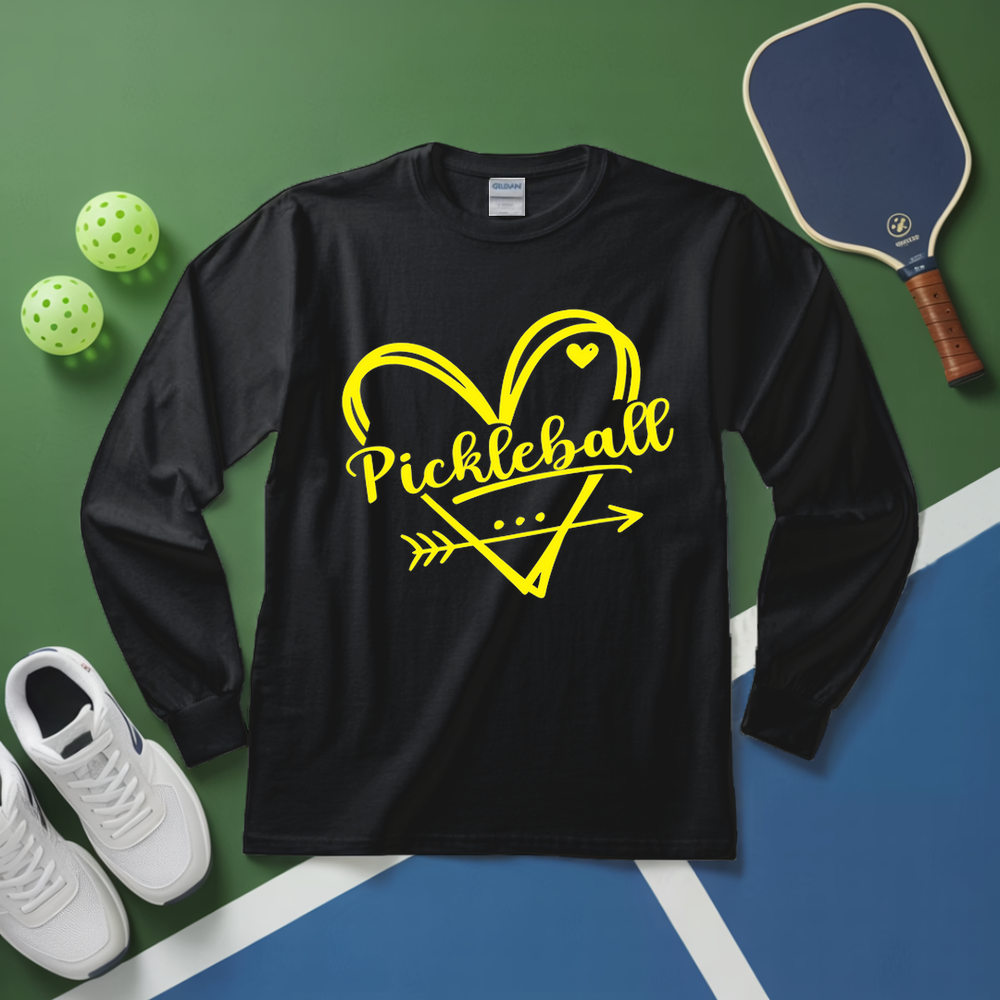 Black long-sleeve shirt with yellow 'Pickleball' design on a green and blue surface with pickleball equipment.