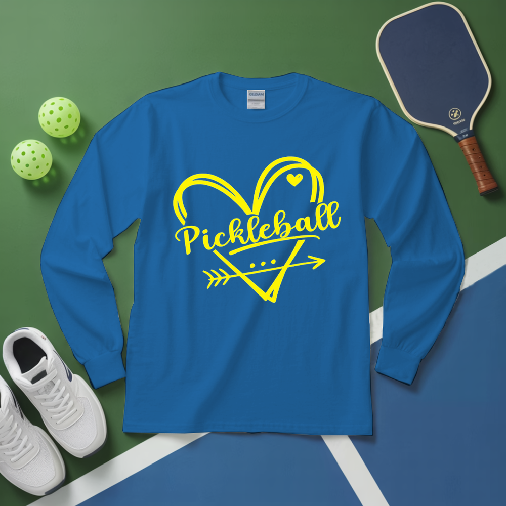 Blue long-sleeve shirt with yellow 'Pickleball' design on a green and blue surface with pickleball equipment.