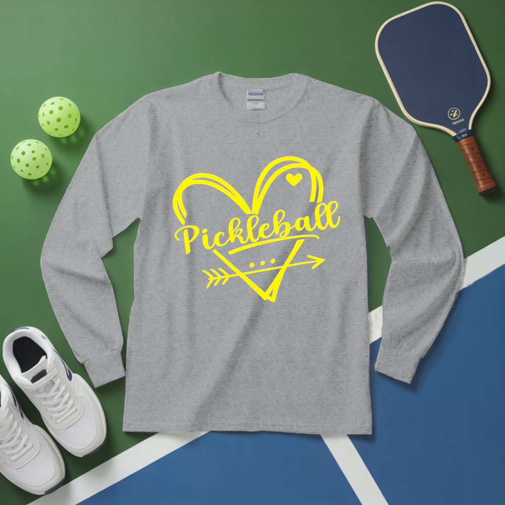 Gray long-sleeve shirt with yellow 'Pickleball' design on a green and blue surface with pickleball equipment.