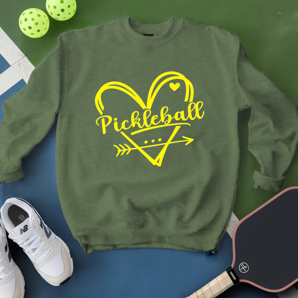 Green sweatshirt with yellow 'Pickleball' design on a blue surface with pickleball equipment.
