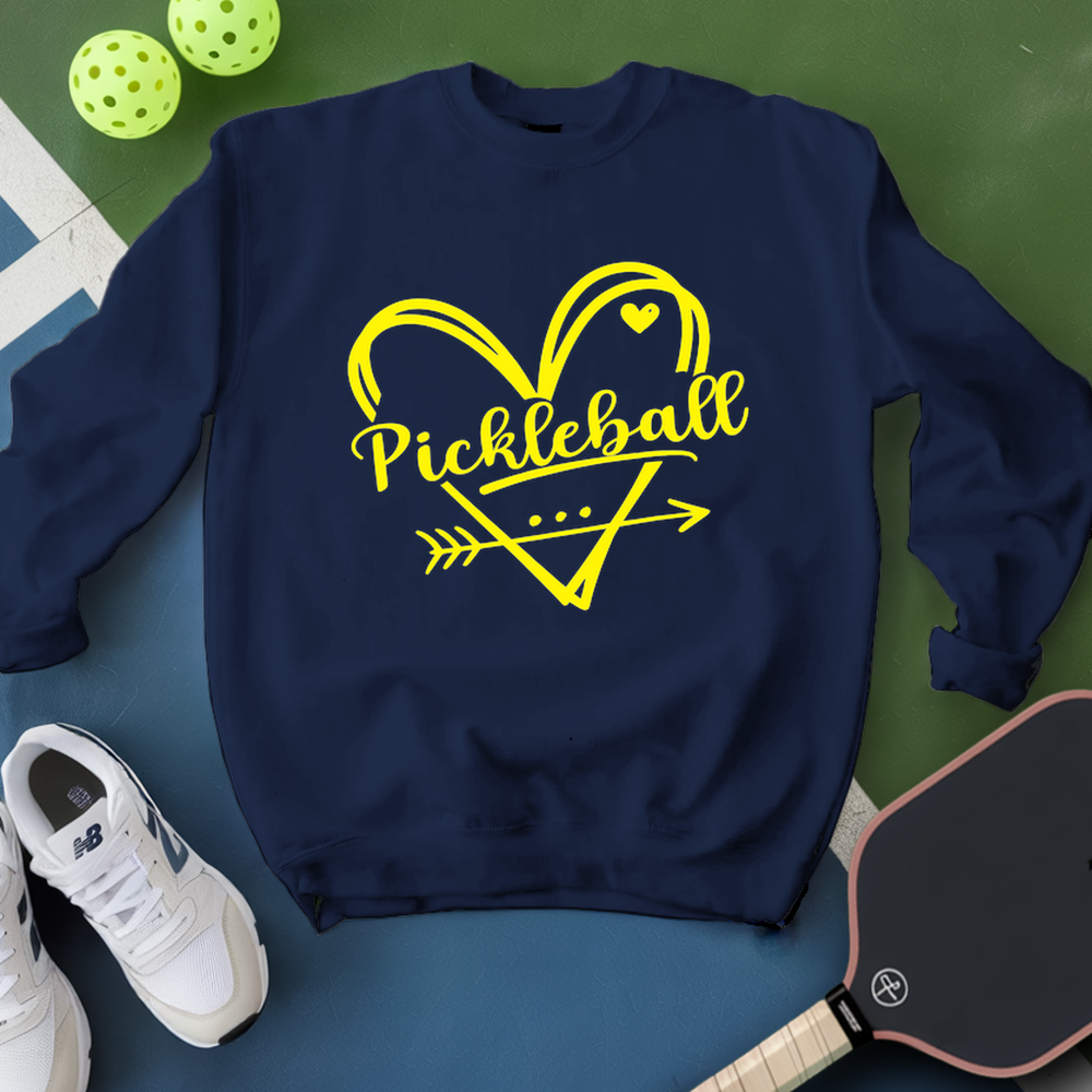 Navy sweatshirt with yellow 'Pickleball' design on a green and blue surface with pickleballs and a paddle.
