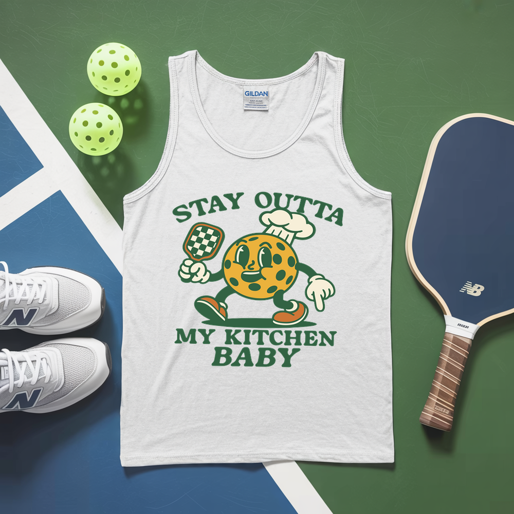 White tank top with cartoon character graphic and text, placed on a green and blue surface with pickleball equipment.