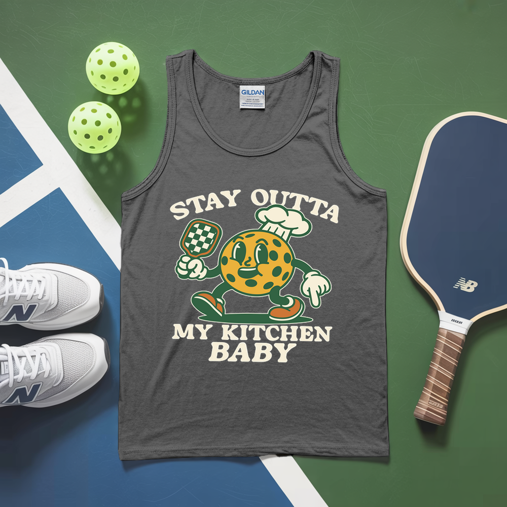 Gray tank top with cartoon character and text, placed on a green and blue surface with pickleballs and a paddle.