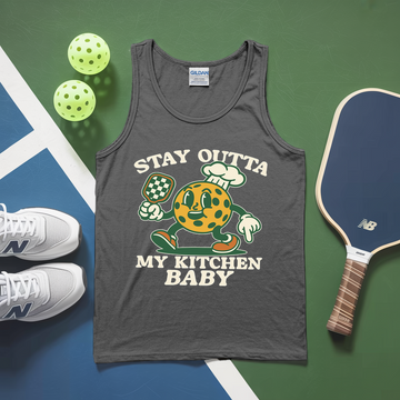Gray tank top with cartoon character and text, placed on a green and blue surface with pickleballs and a paddle.