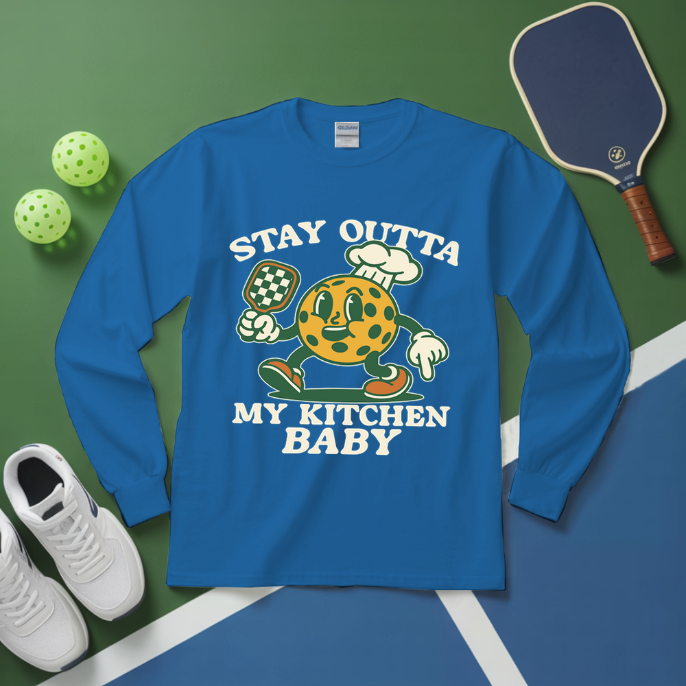 Blue long-sleeve shirt with cartoon character and text on a green and blue surface with sports equipment.