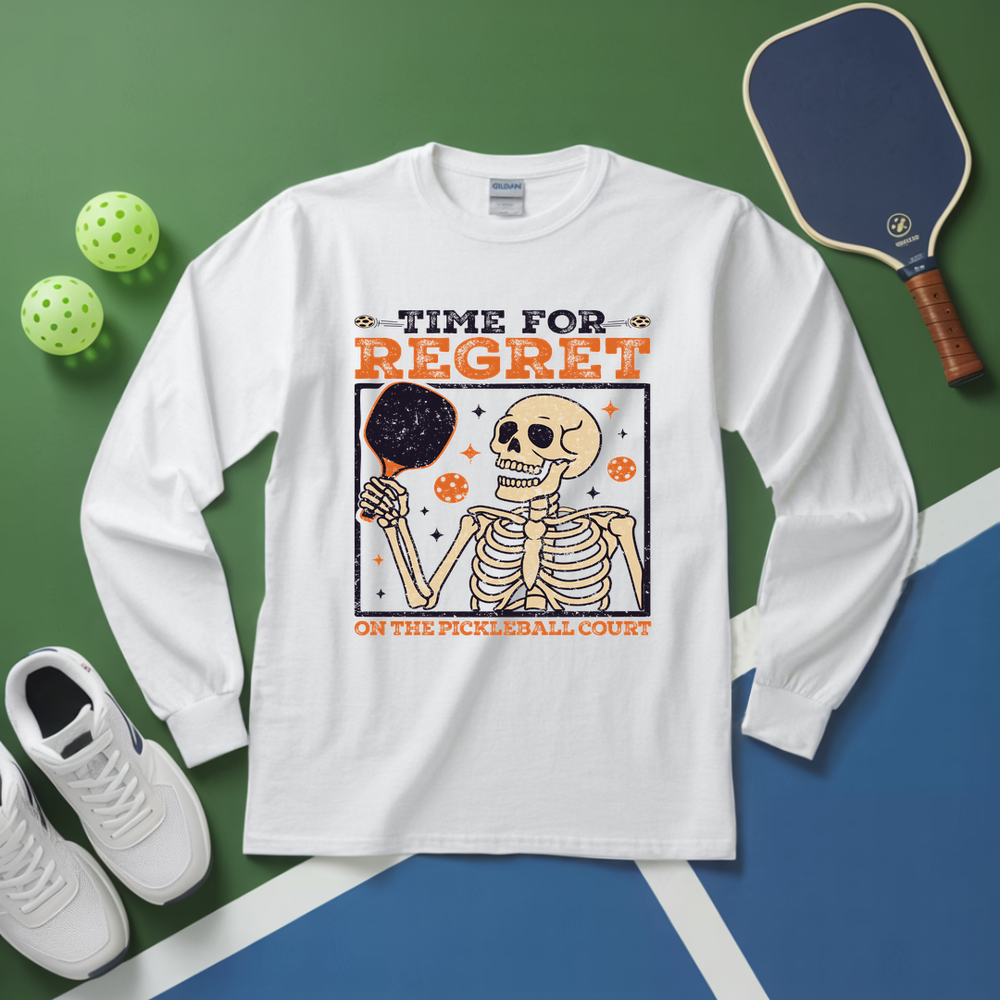 White long-sleeve shirt with skeleton design and text on a green and blue background with pickleball equipment.