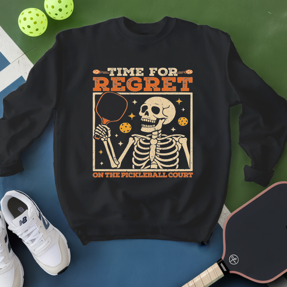 Black sweatshirt with skeleton design and text on a blue and green background with pickleball equipment.