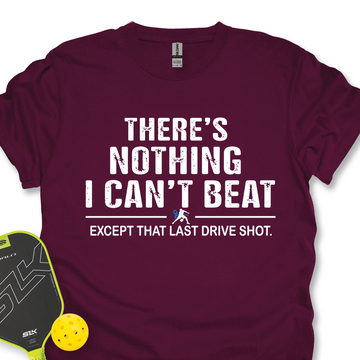 Maroon t-shirt with motivational text and pickleball equipment on a white background