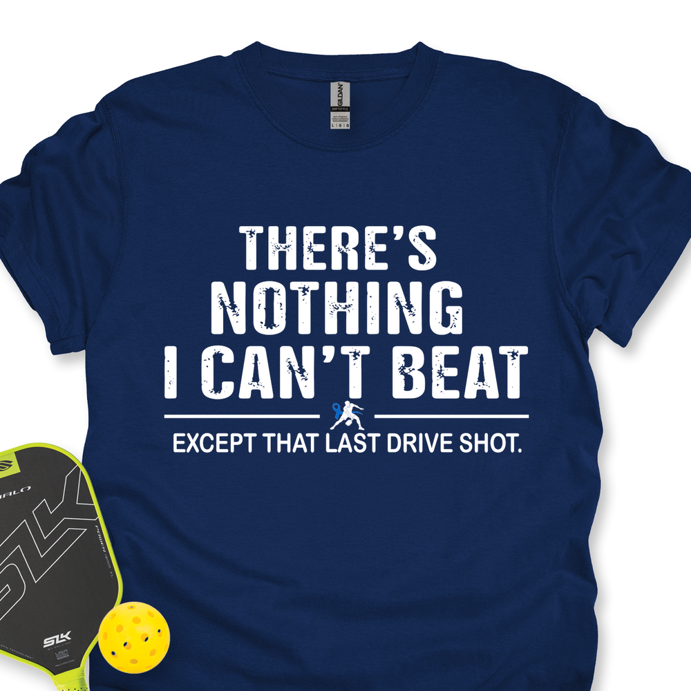 Navy blue t-shirt with humorous text design, placed next to a pickleball paddle and ball on a white background.