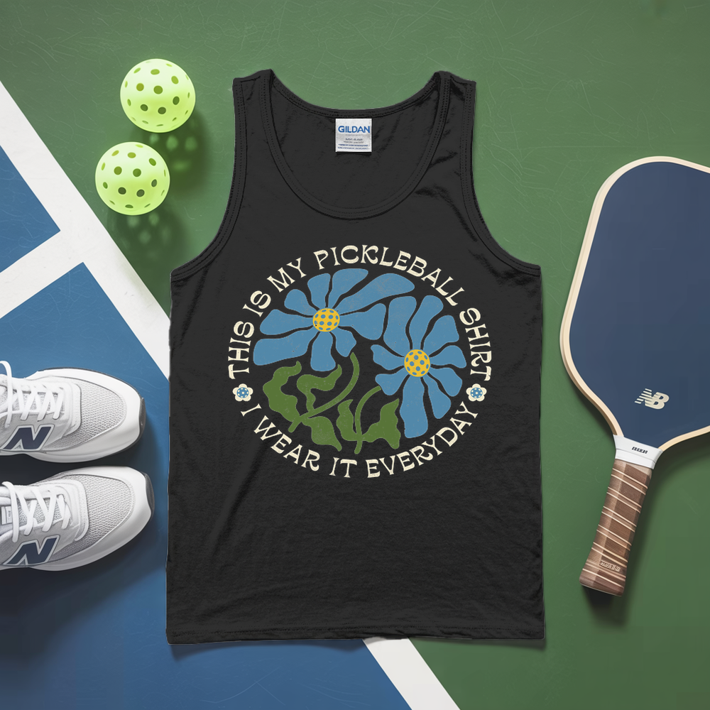 Black tank top with pickleball design on a green and blue surface with pickleballs and a paddle.